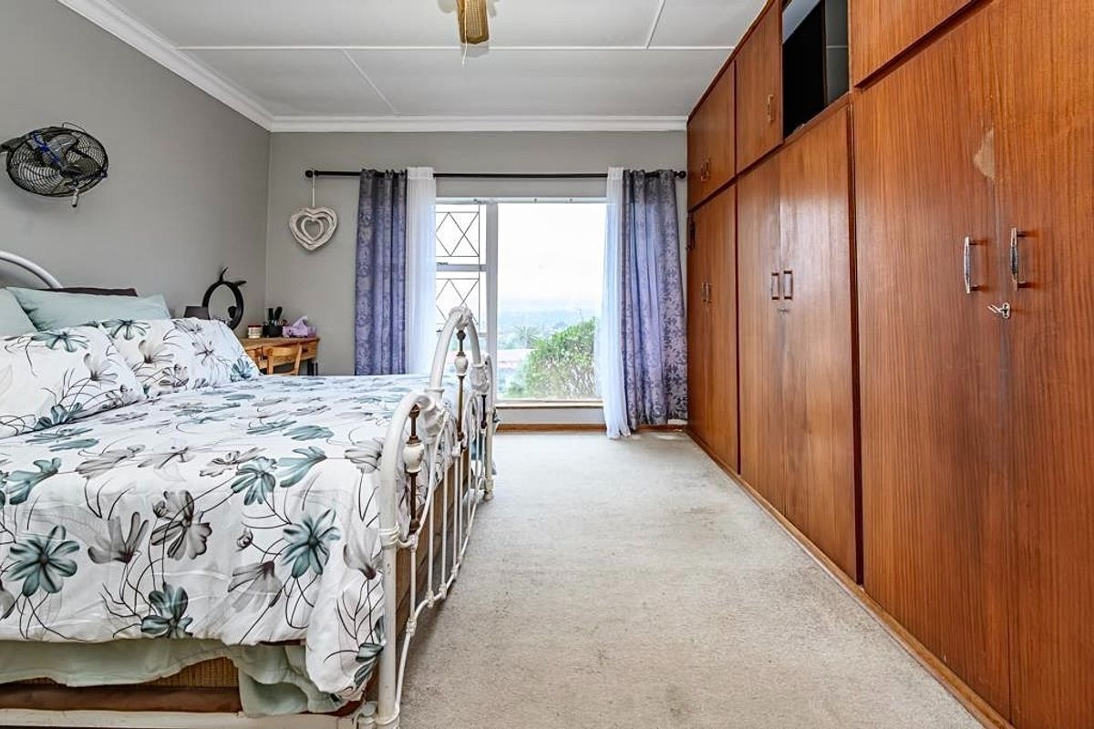 A bedroom featuring extensive built-in wooden cabinetry, carpeted flooring, and a window with security bars offering natural light.