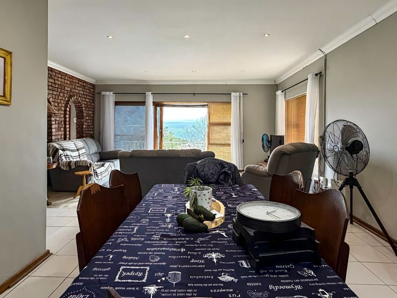 Open-plan living and dining area featuring an exposed brick wall, tiled flooring, and sliding doors leading to an outdoor view.