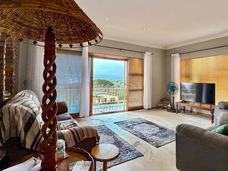 Spacious living room featuring polished concrete floors, an exposed brick accent wall, and large sliding doors opening to a balcony with scenic views.