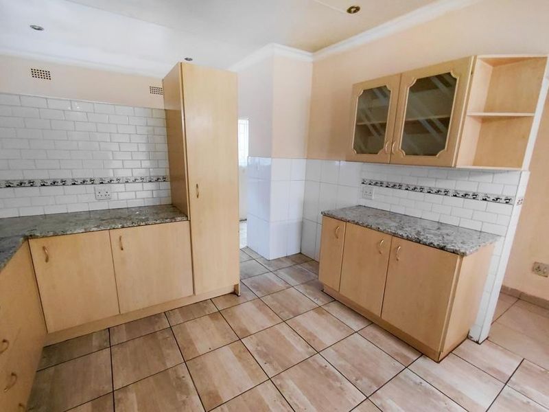 A functional kitchen featuring light wood cabinetry, granite countertops, and a classic subway tile backsplash with neutral ceramic floor tiling.