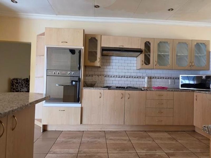 A functional kitchen featuring granite countertops, built-in oven, gas hob, and subway tile backsplash, with tiled flooring throughout.
