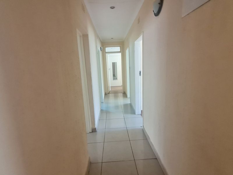 A functional hallway featuring tiled flooring and recessed lighting, providing access to multiple rooms throughout the property.