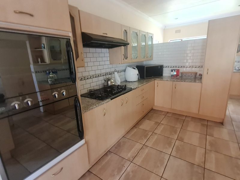 Functional kitchen featuring light wood cabinetry, granite countertops, a built-in oven, gas hob, and a classic subway tile backsplash.