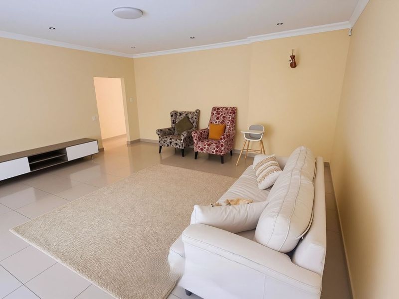 A spacious living room featuring neutral wall tones, tiled flooring, and recessed downlighting, providing a clean and versatile foundation for interior design.