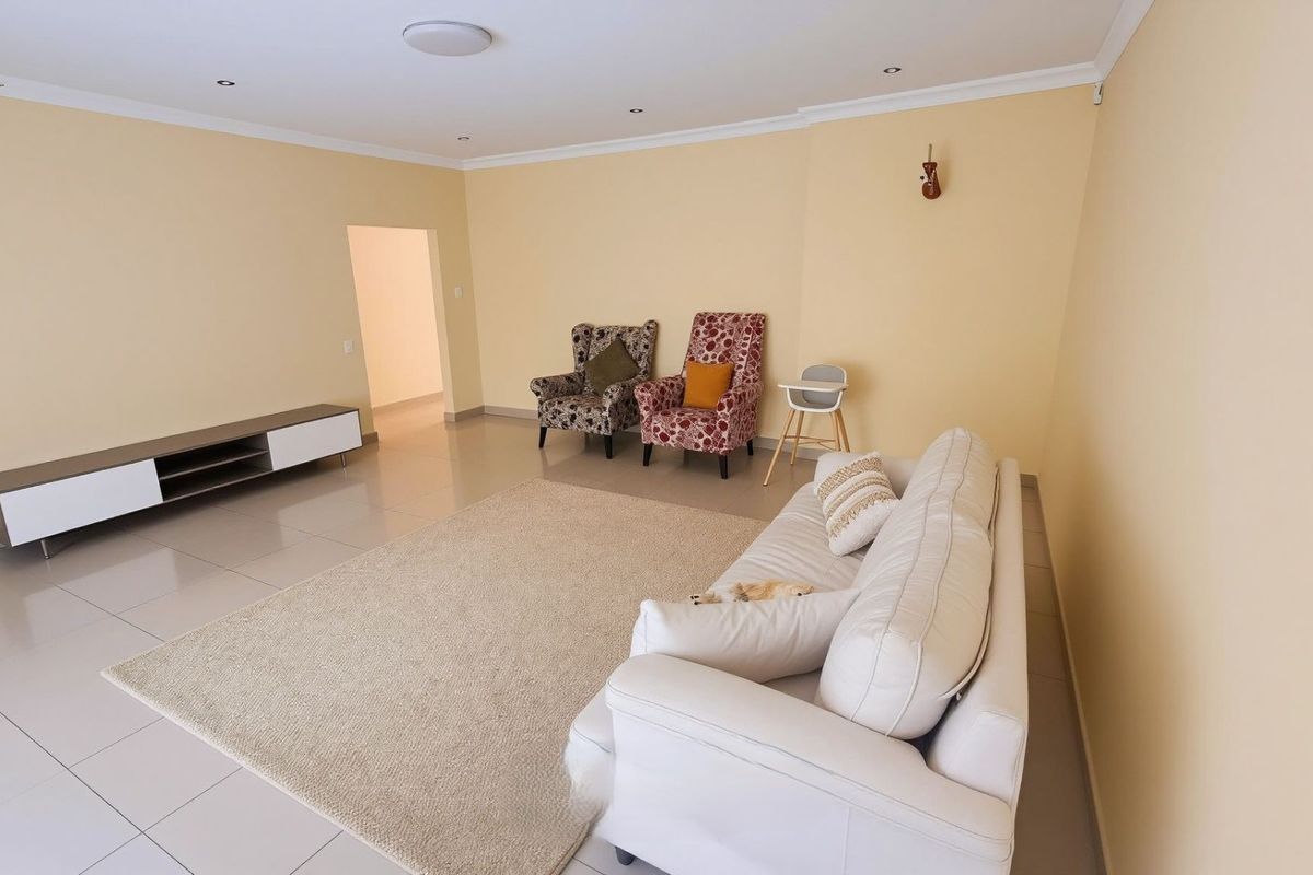 A spacious living room featuring neutral wall tones, tiled flooring, and recessed downlighting, providing a clean and versatile foundation for interior design.