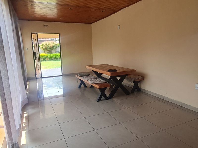 A covered patio area featuring tiled flooring and a timber ceiling, with direct access to the garden through sliding glass doors.