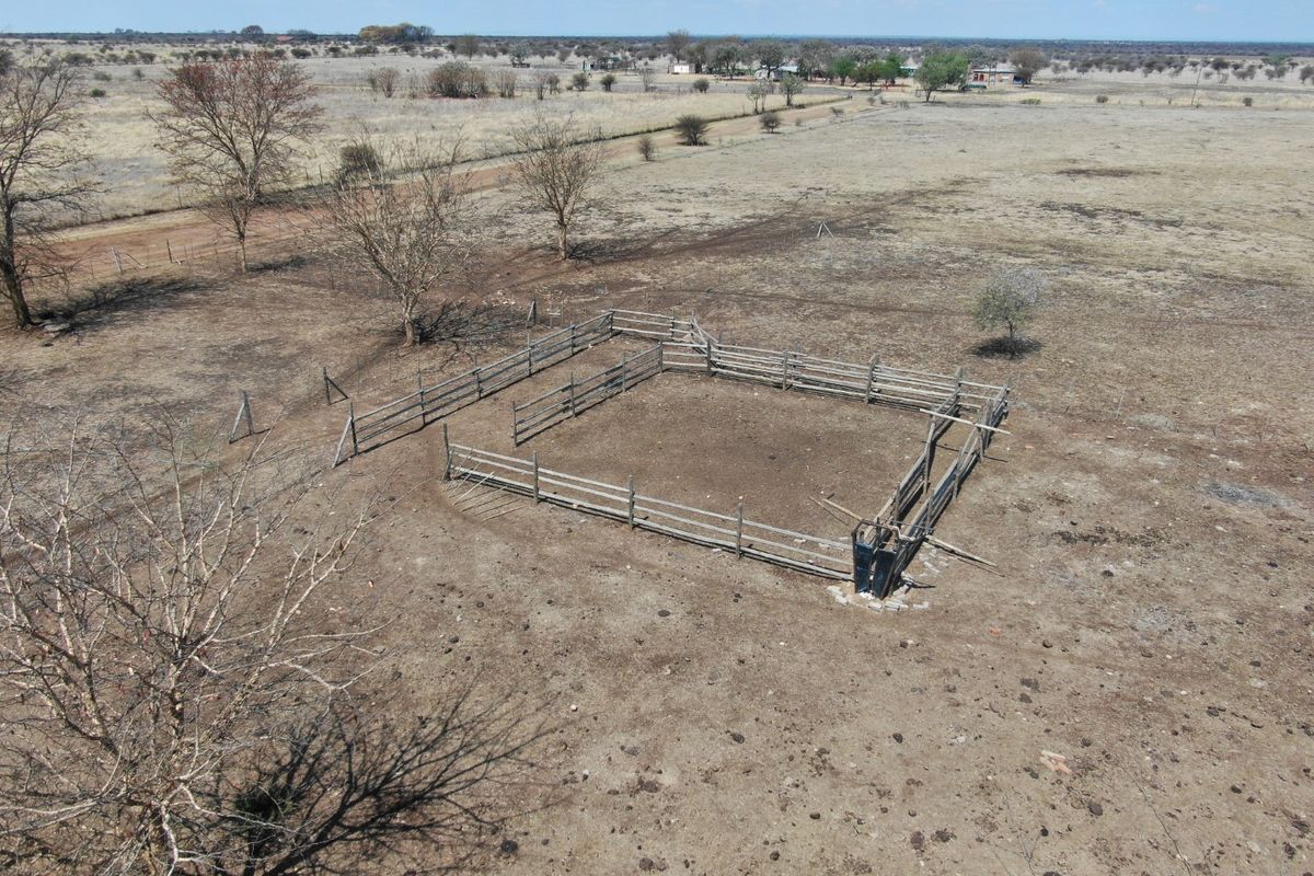 Aerial view of a farm property featuring a livestock kraal with wooden fencing and a cattle crush set in an open field.