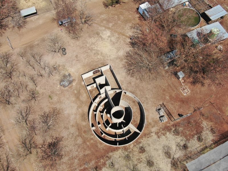 Aerial view of an incomplete circular masonry structure on a rural farm property, showing the foundation and wall layout.