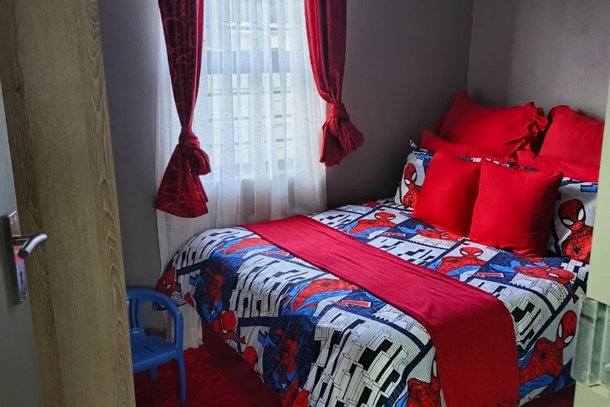 A compact bedroom featuring tiled flooring and neutral wall finishes, providing a functional space for a single bed.