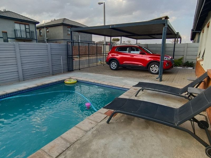 Outdoor pool area featuring a swimming pool, paved patio space, and a covered carport structure.
