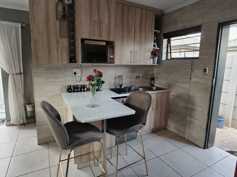 Modern kitchen featuring light wood-tone cabinetry, a breakfast counter, tiled finishes, and integrated microwave, offering a functional and contemporary cooking space.