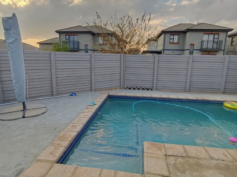 Outdoor pool area featuring a swimming pool with tiled coping, perimeter fencing, and paved patio space.