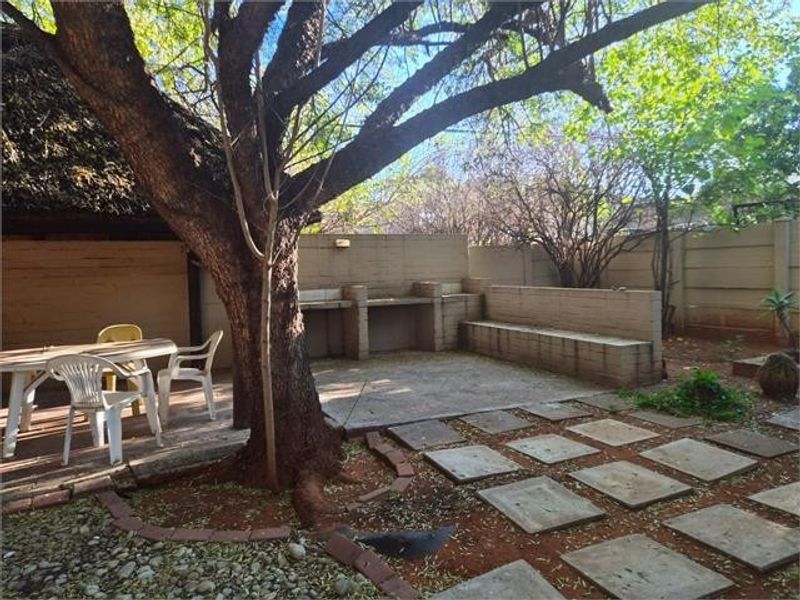 Rear garden area featuring a paved patio, built-in braai, and boundary wall, offering a functional outdoor entertainment space.