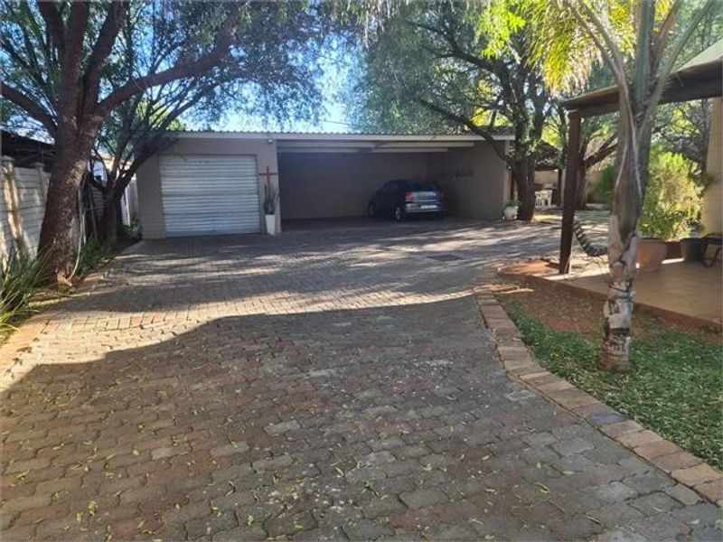 A paved driveway leading to a single enclosed garage and an adjacent open carport area.