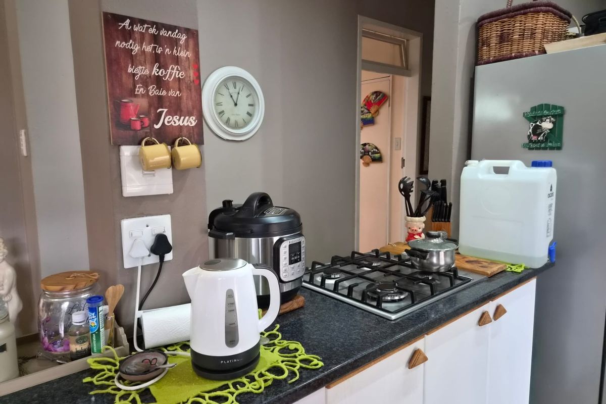 A functional kitchen area featuring a gas hob, dark laminate countertops, and white built-in cabinetry, providing a practical workspace for daily cooking.