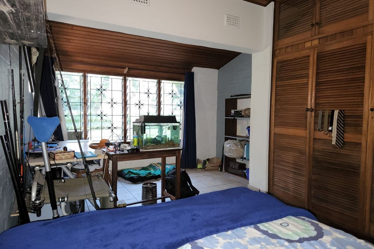 Bedroom featuring a timber-paneled ceiling, tiled flooring, and extensive built-in timber wardrobe storage with security bars on the windows.