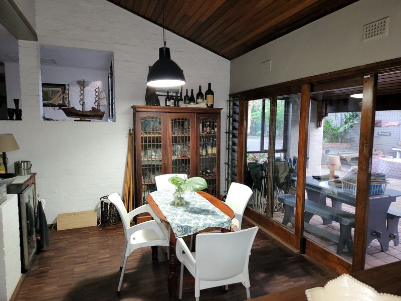 Dining area featuring parquet flooring, exposed brick walls, timber ceiling, and large sliding glass doors providing access to the outdoor patio.