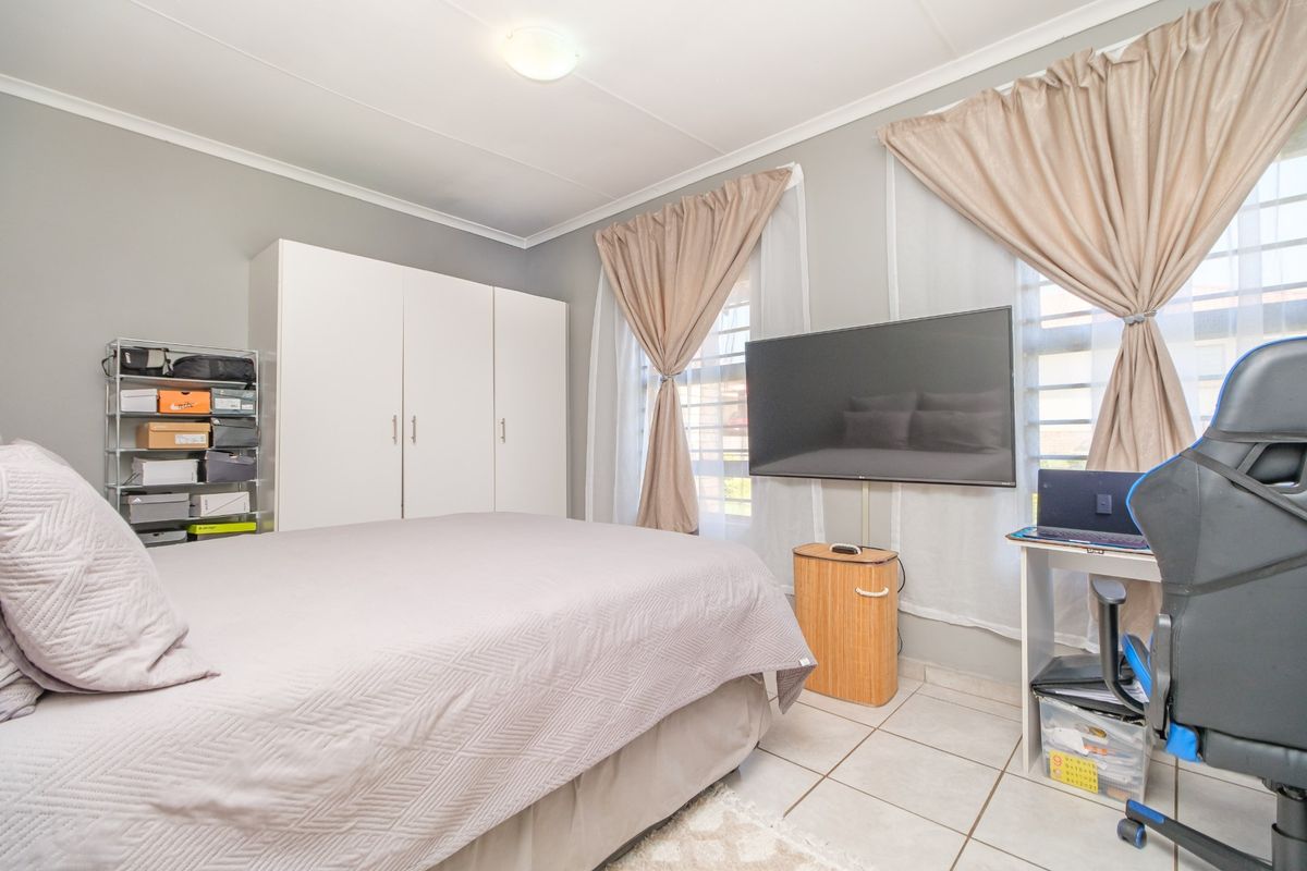 A functional bedroom featuring tiled flooring, a built-in wardrobe, and neutral wall tones, offering a practical and comfortable living space.