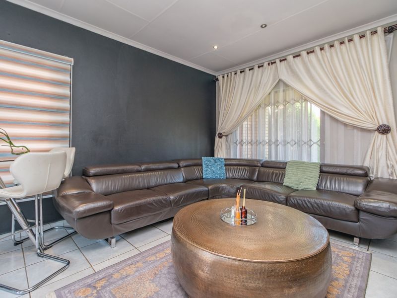 A well-maintained living room featuring tiled flooring, recessed downlighting, and a dark accent wall, providing a comfortable and functional living space.