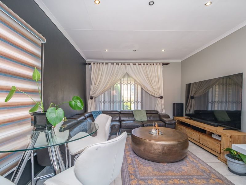 A well-maintained living room featuring tiled flooring, recessed downlighting, and a security gate on the window.