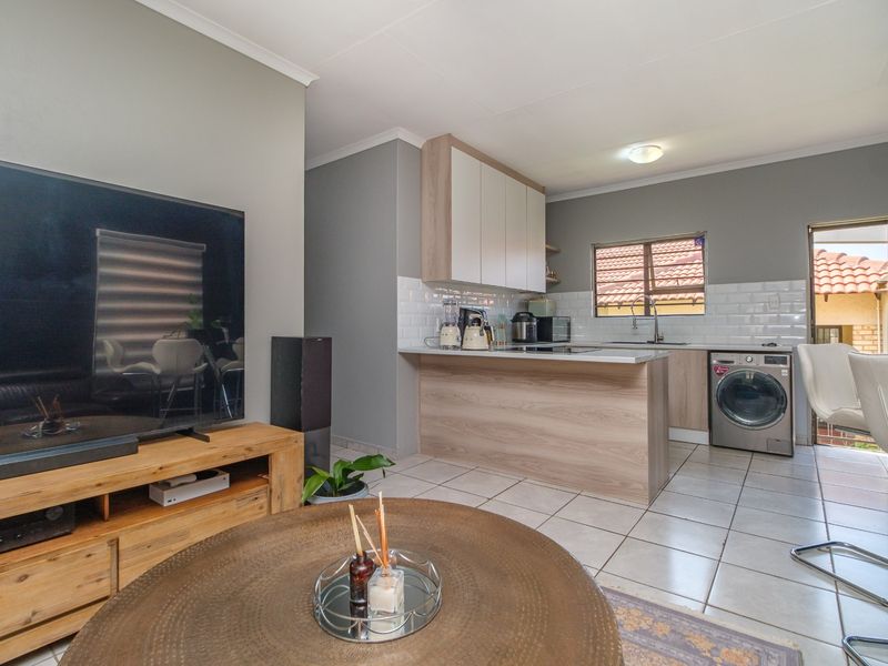 An open-plan living and kitchen area featuring modern cabinetry, a subway tile backsplash, and tiled flooring, creating a functional and cohesive living space.