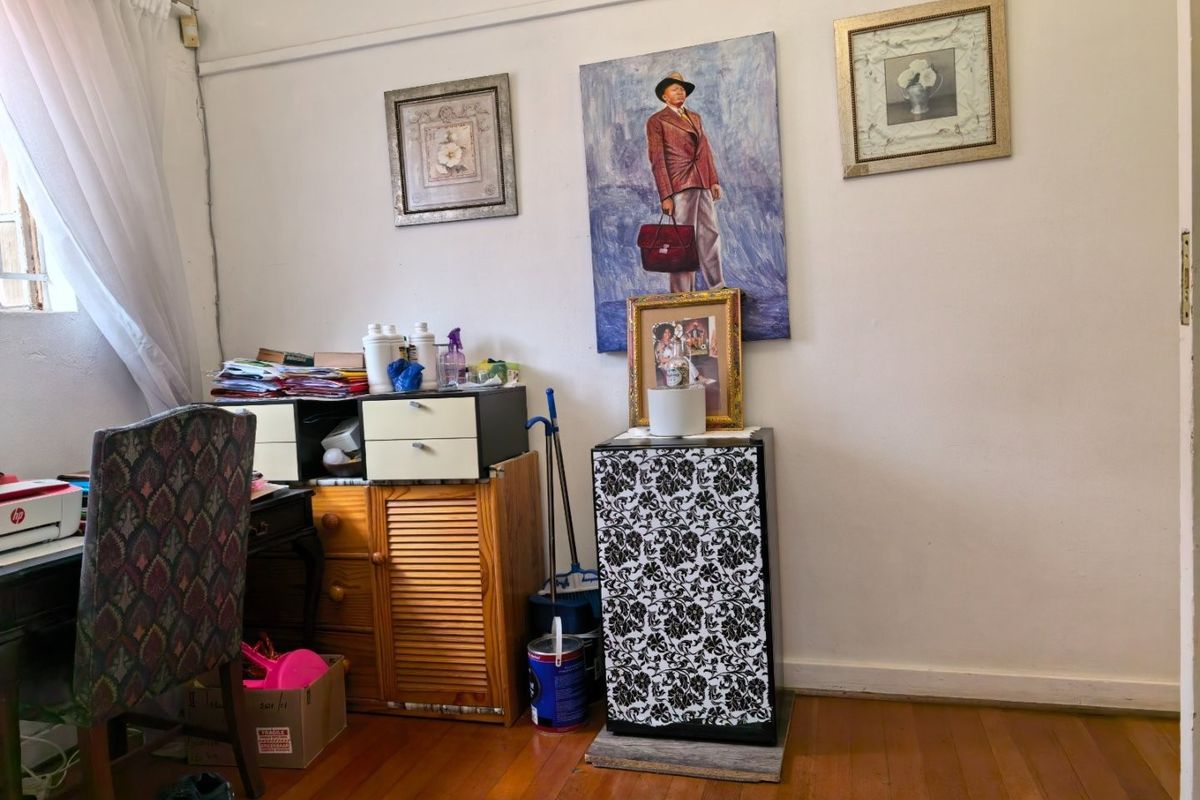 A bedroom space featuring hardwood flooring and a window with a curtain rail, currently utilized as a home office area.