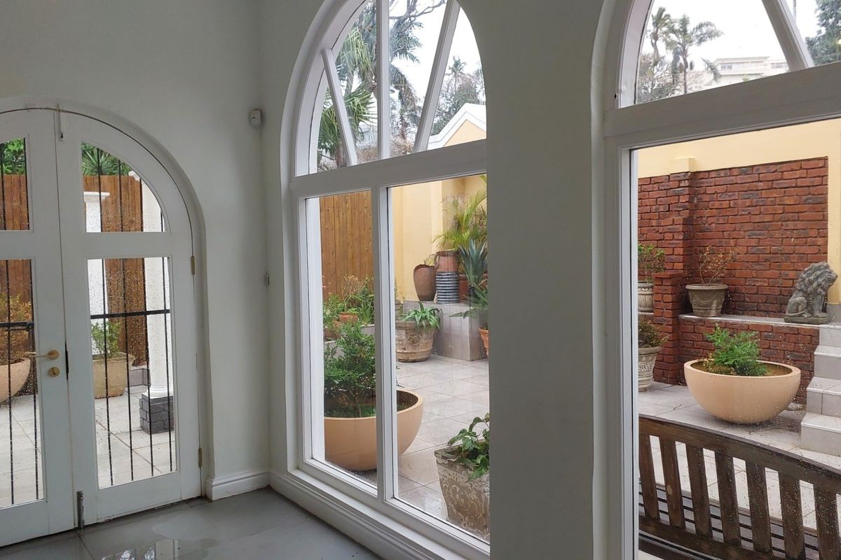 Bright office space featuring large arched windows and double doors providing direct access to a private paved courtyard area.
