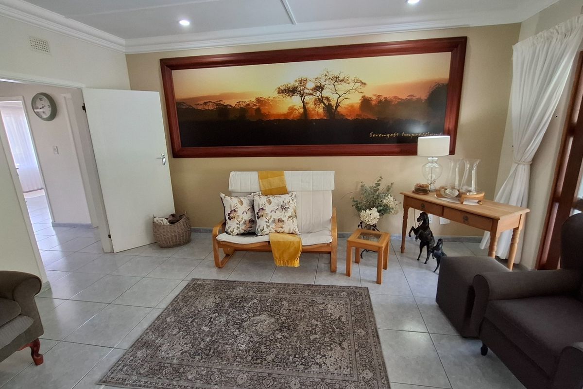 A well-maintained living room featuring neutral tiled flooring, recessed downlighting, and decorative ceiling cornicing, creating a bright and inviting atmosphere.
