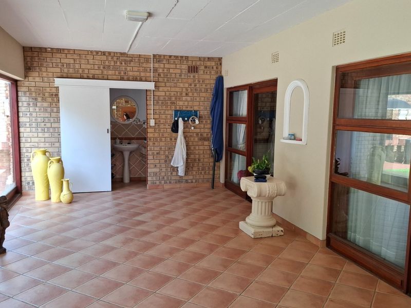 Spacious enclosed patio featuring exposed brick walls, tiled flooring, and direct access to a secondary wash area with a pedestal sink.
