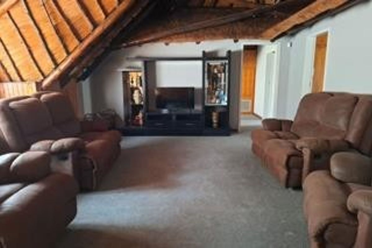 Spacious living room featuring a high-pitched exposed thatch roof with timber trusses, creating a rustic and airy atmosphere.