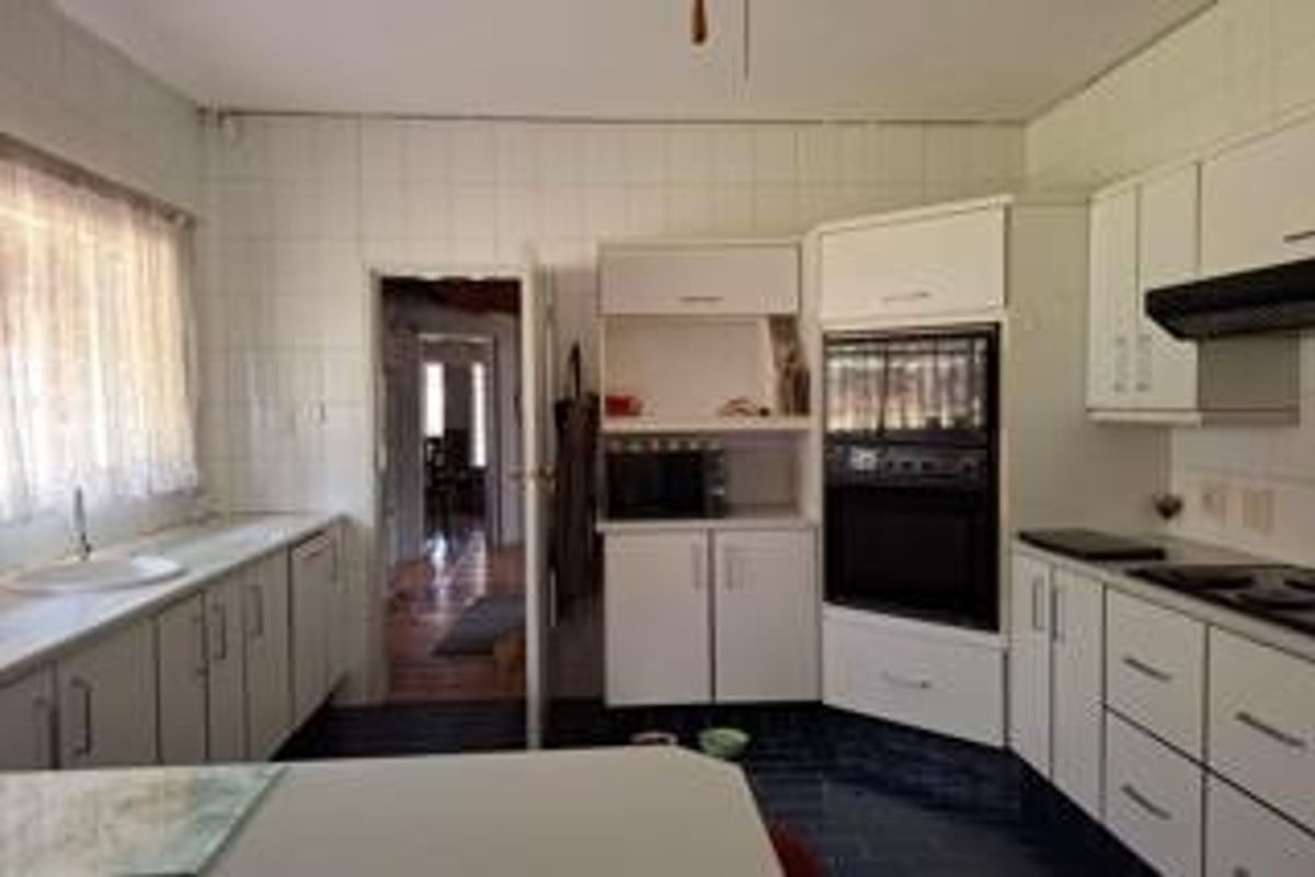 A functional kitchen featuring white built-in cabinetry, a built-in oven, extractor fan, and tiled wall finishes, offering a classic layout with ample storage space.