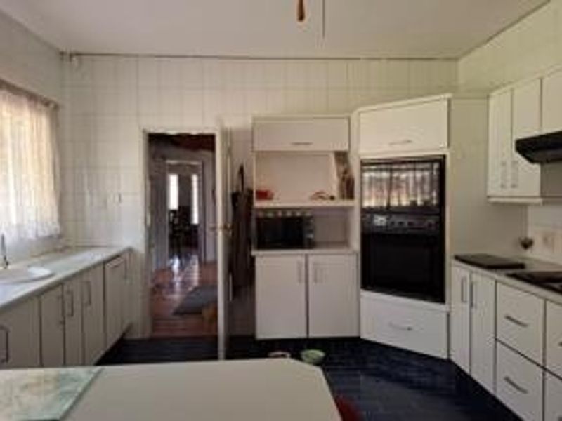 A functional kitchen featuring white built-in cabinetry, a built-in oven, extractor fan, and tiled wall finishes, offering a classic layout with ample storage space.