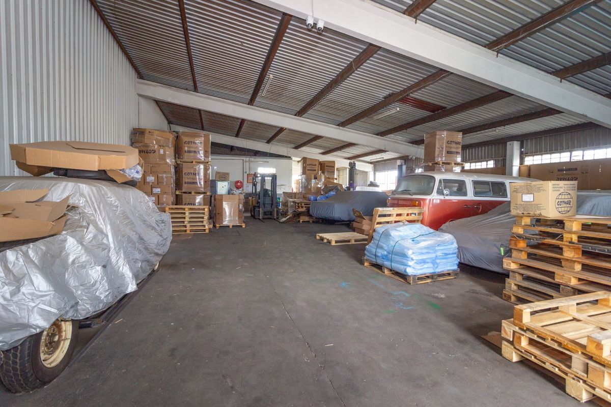 Spacious industrial utility area featuring high corrugated metal ceilings, exposed steel structural beams, and durable concrete flooring, suitable for storage or workshop use.