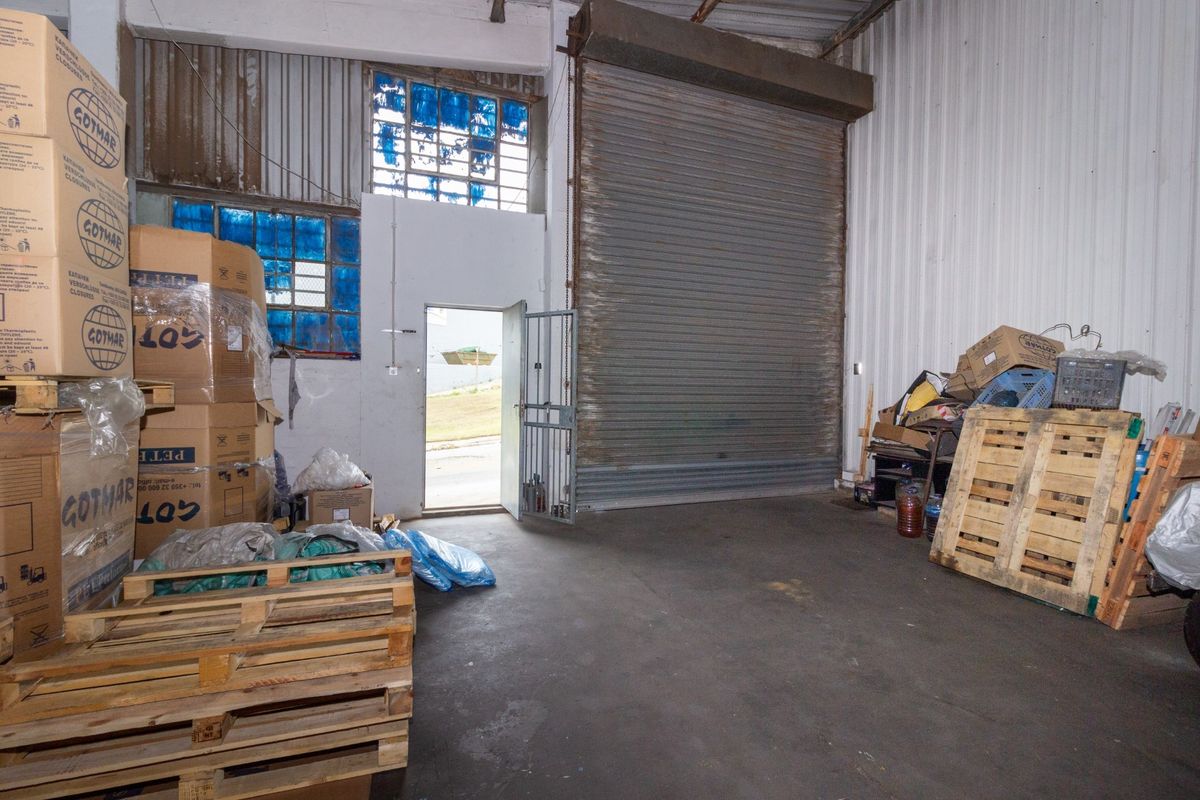 Industrial warehouse space featuring a large roller shutter door, high ceilings, and secure access, suitable for storage or light manufacturing operations.