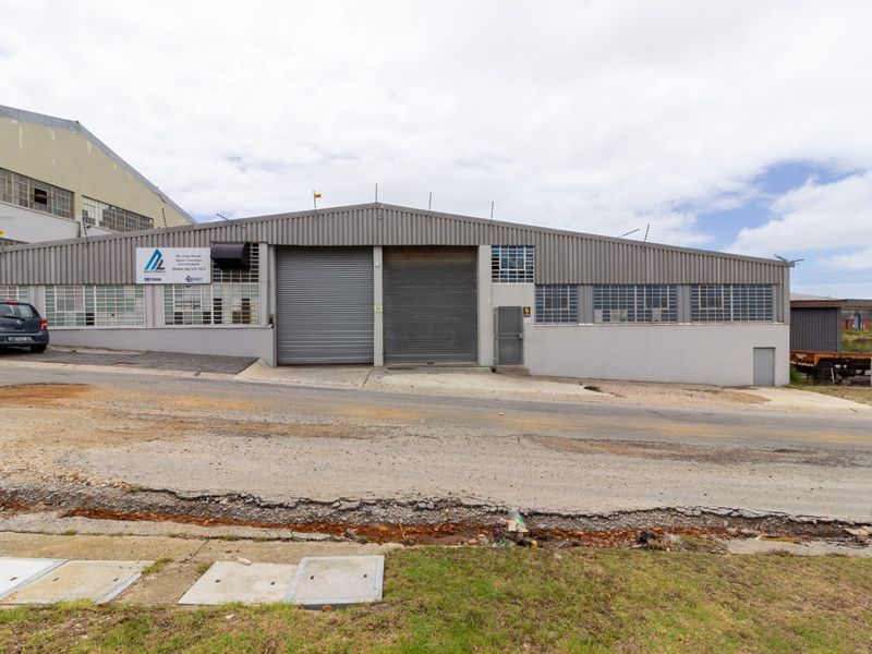 Front elevation of an industrial warehouse featuring dual roller shutter doors, steel-framed windows, and corrugated metal cladding.