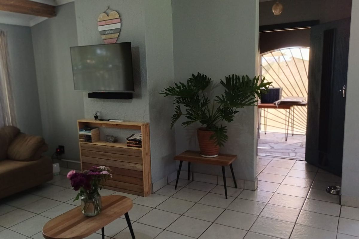 A living room featuring tiled flooring, a built-in wall niche, and an archway leading to an outdoor patio area.
