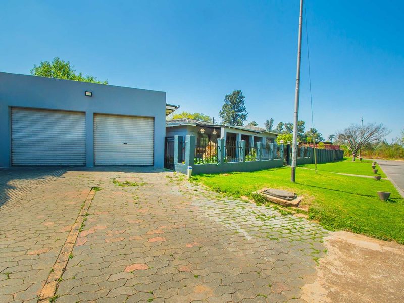 Front view of the property featuring a double garage with roller shutter doors, a paved driveway, and a fenced front garden area.