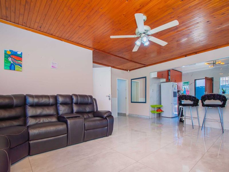 Open plan living area featuring tiled flooring and a timber tongue and groove ceiling, seamlessly connecting to a functional kitchen space.