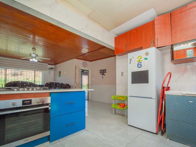 Kitchen area featuring blue cabinetry, built-in oven, gas hob, and tiled flooring, with visible ceiling damage requiring repair.