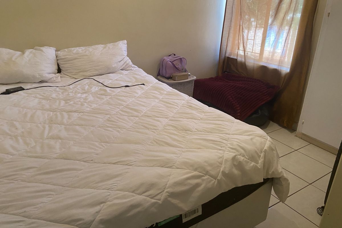A bedroom featuring tiled flooring and a window with curtains.