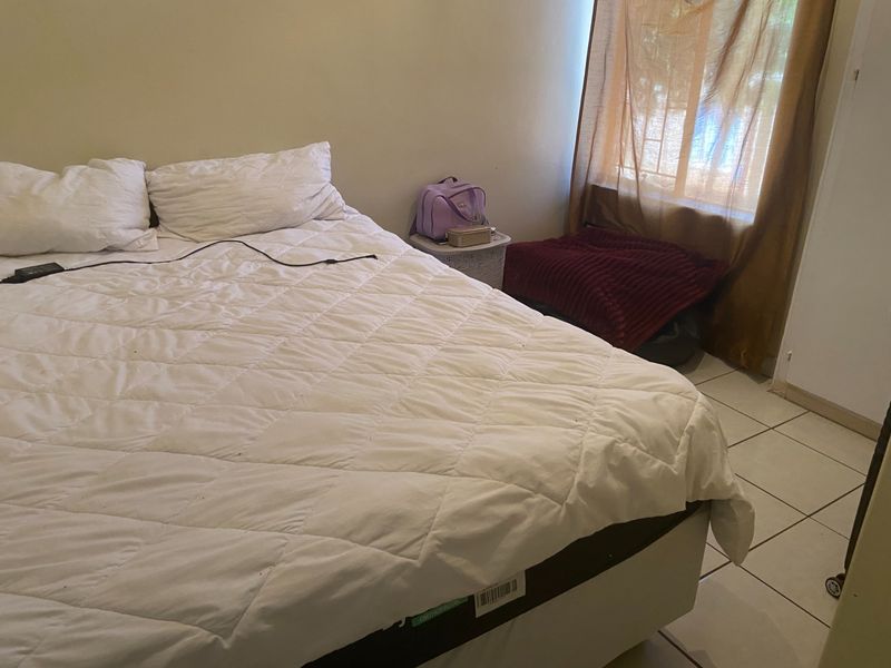 A bedroom featuring tiled flooring and a window with curtains.