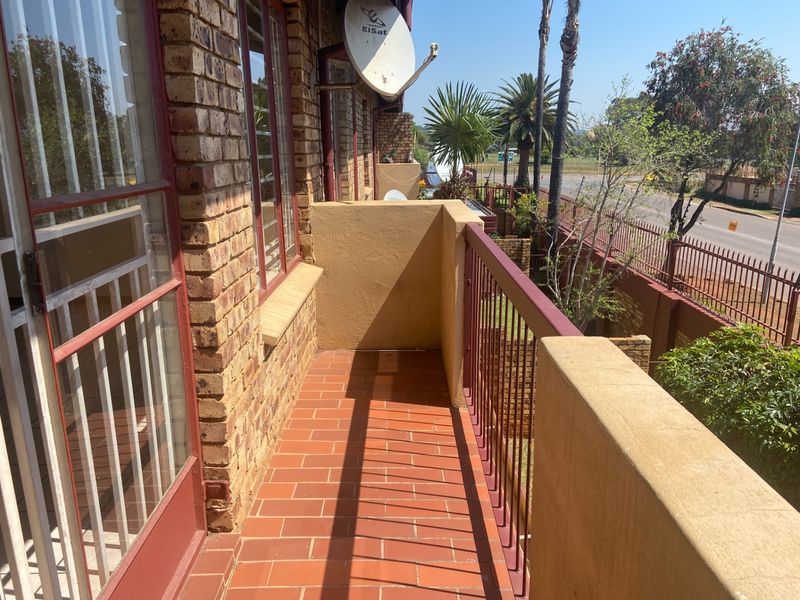 A private balcony featuring terracotta tile flooring, face brick exterior walls, and a metal balustrade overlooking the street and surrounding area.