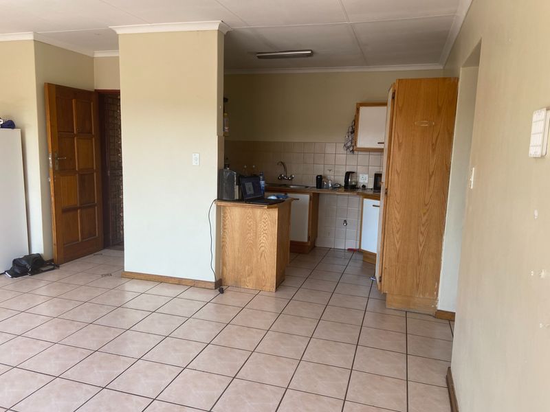 Open plan living area featuring tiled flooring and a compact kitchen with built-in cabinetry and sink.