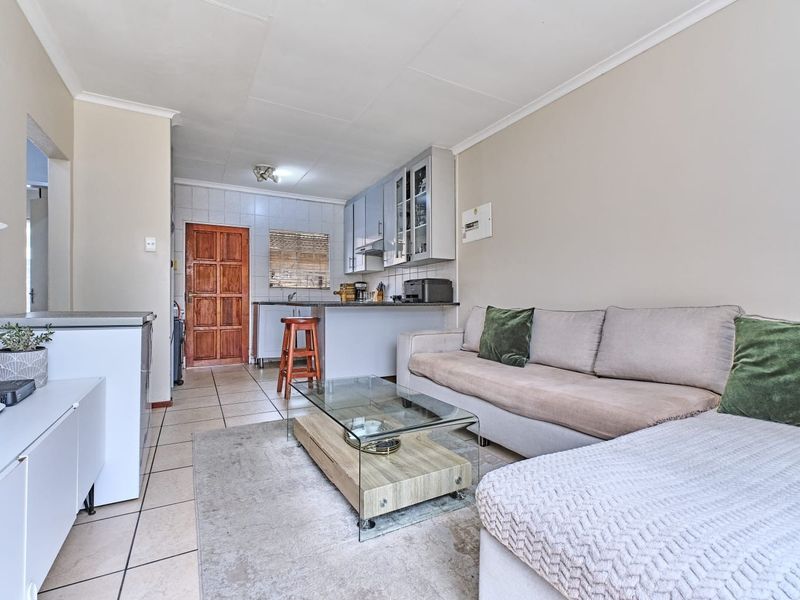 Open-plan living area featuring tiled flooring and a compact kitchen with built-in cabinetry, providing a functional layout for daily living.