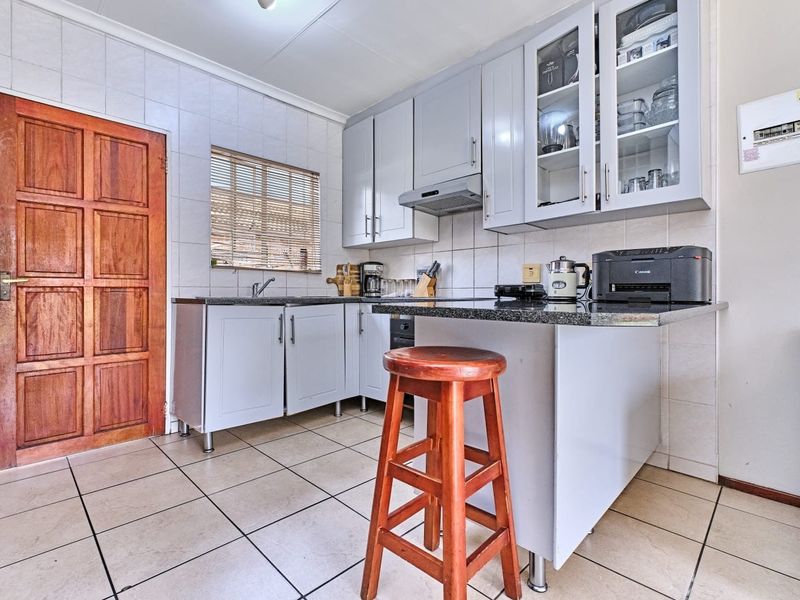 A functional kitchen featuring light-toned cabinetry, granite countertops, tiled backsplash, and tiled flooring, providing a practical workspace with integrated storage and ventilation.