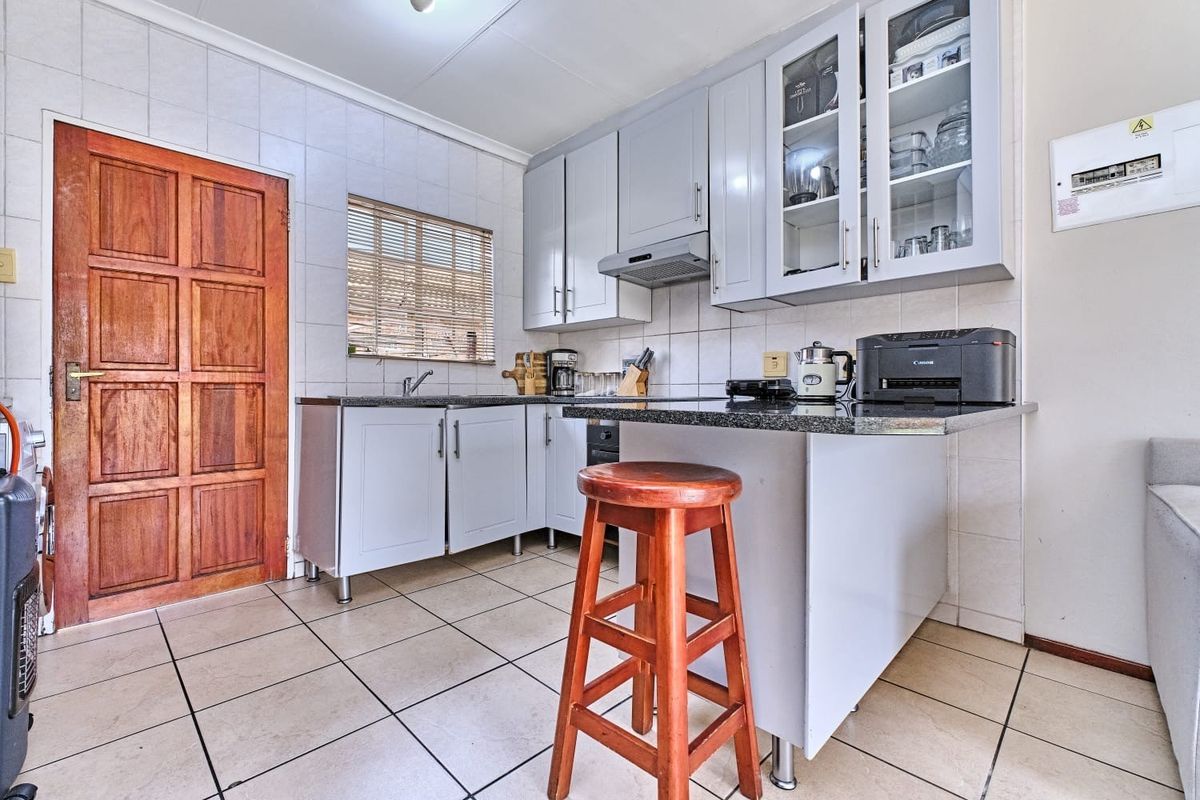 A functional kitchen featuring light-toned cabinetry, granite countertops, tiled backsplash, and tiled flooring, providing a practical workspace with integrated storage and ventilation.