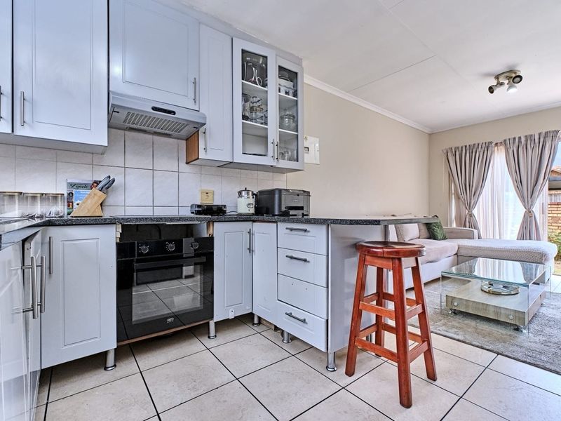Open-plan kitchen and living area featuring light-toned cabinetry, granite countertops, built-in oven, and direct access to the outdoor patio through a sliding door.