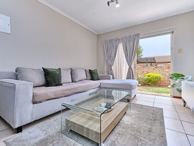 A bright living room featuring tiled flooring and a sliding glass door providing direct access to the rear garden area.
