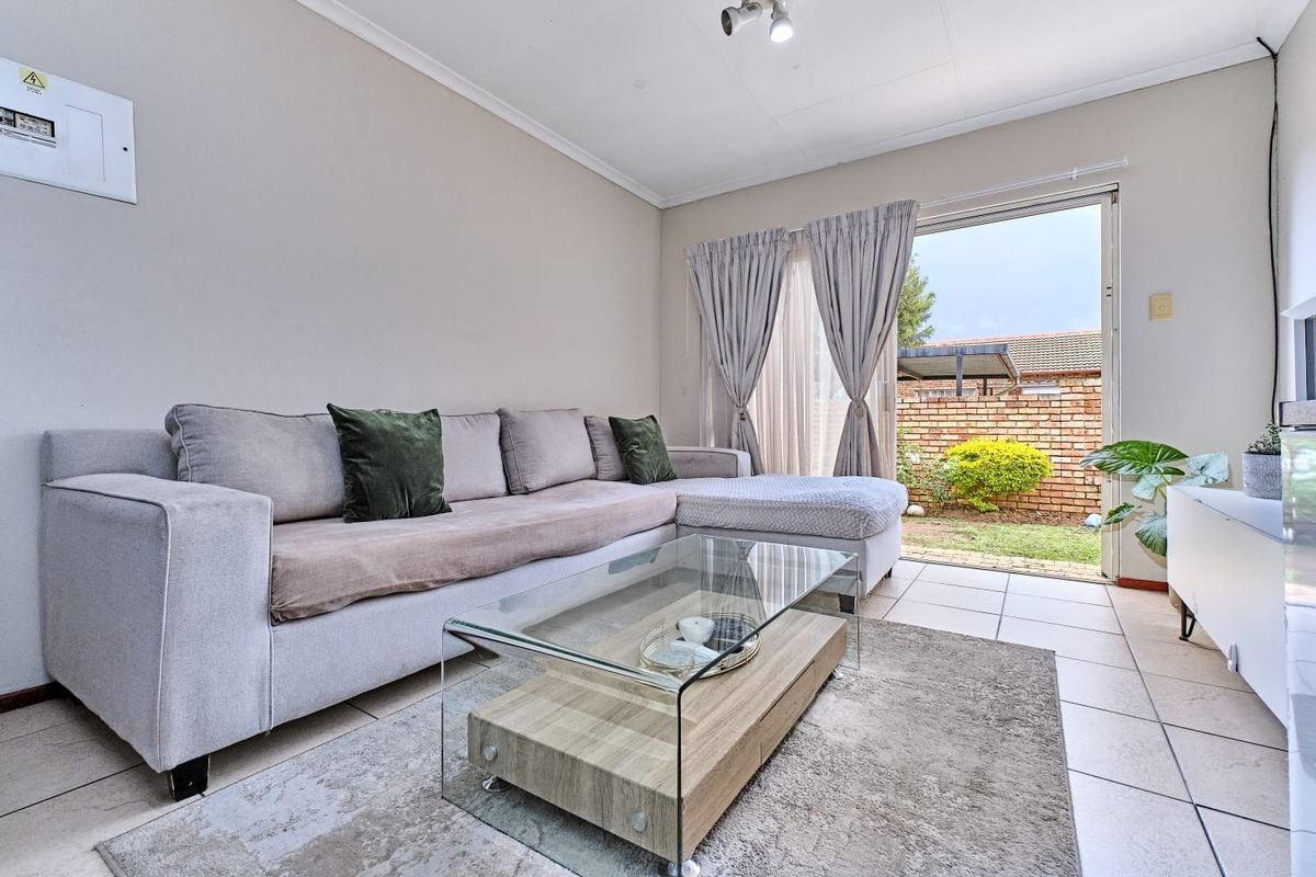 A bright living room featuring tiled flooring and a sliding glass door providing direct access to the rear garden area.