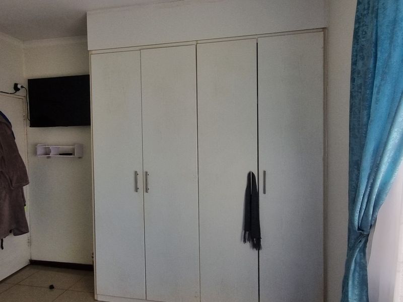 Bedroom featuring white built-in cupboards and tiled flooring, providing functional storage space within the apartment.